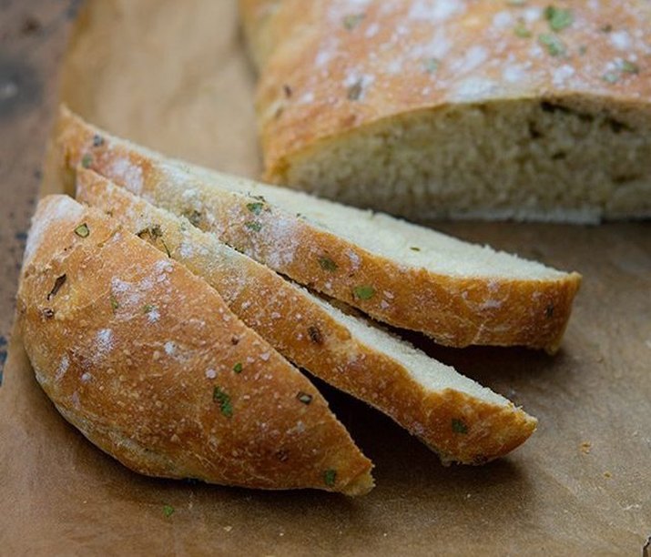 Sliced herbed bread on a wooden cutting board