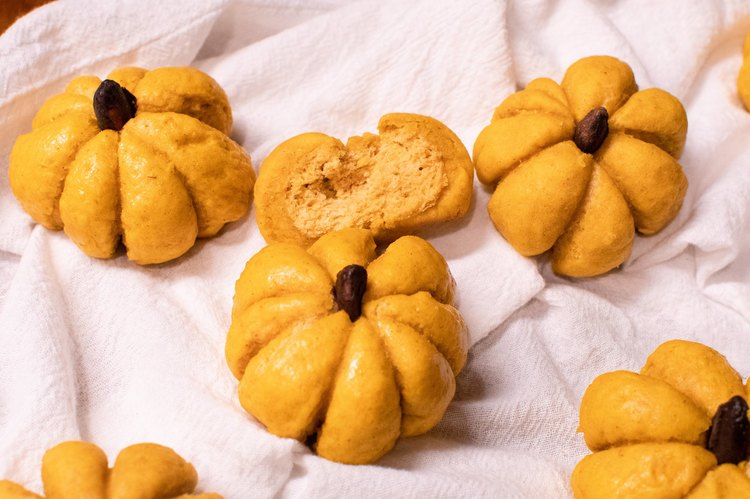 Pumpkin-shaped dinner rolls against a white napkin
